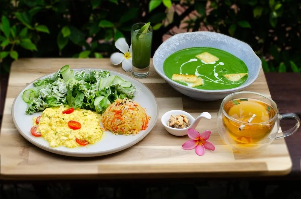 Vegetarian plate with green soup, a yellow scramble, and salad