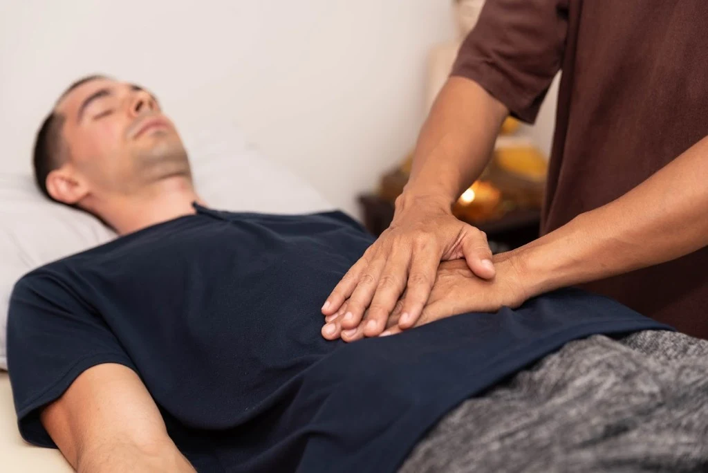 Reiki session — practitioner placing hands on guest